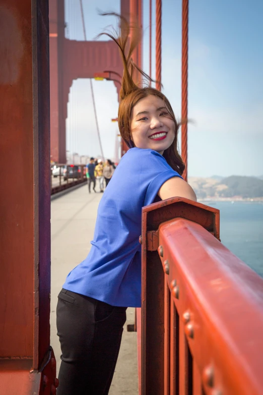 a young lady standing on a bridge next to the ocean