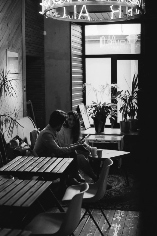 a couple sitting at table next to a window