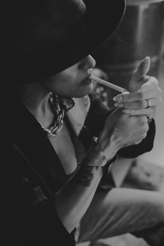 black and white pograph of woman holding cigarette in her mouth