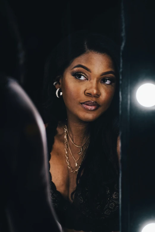 a woman with a dark shirt and hoop earrings looking in the mirror