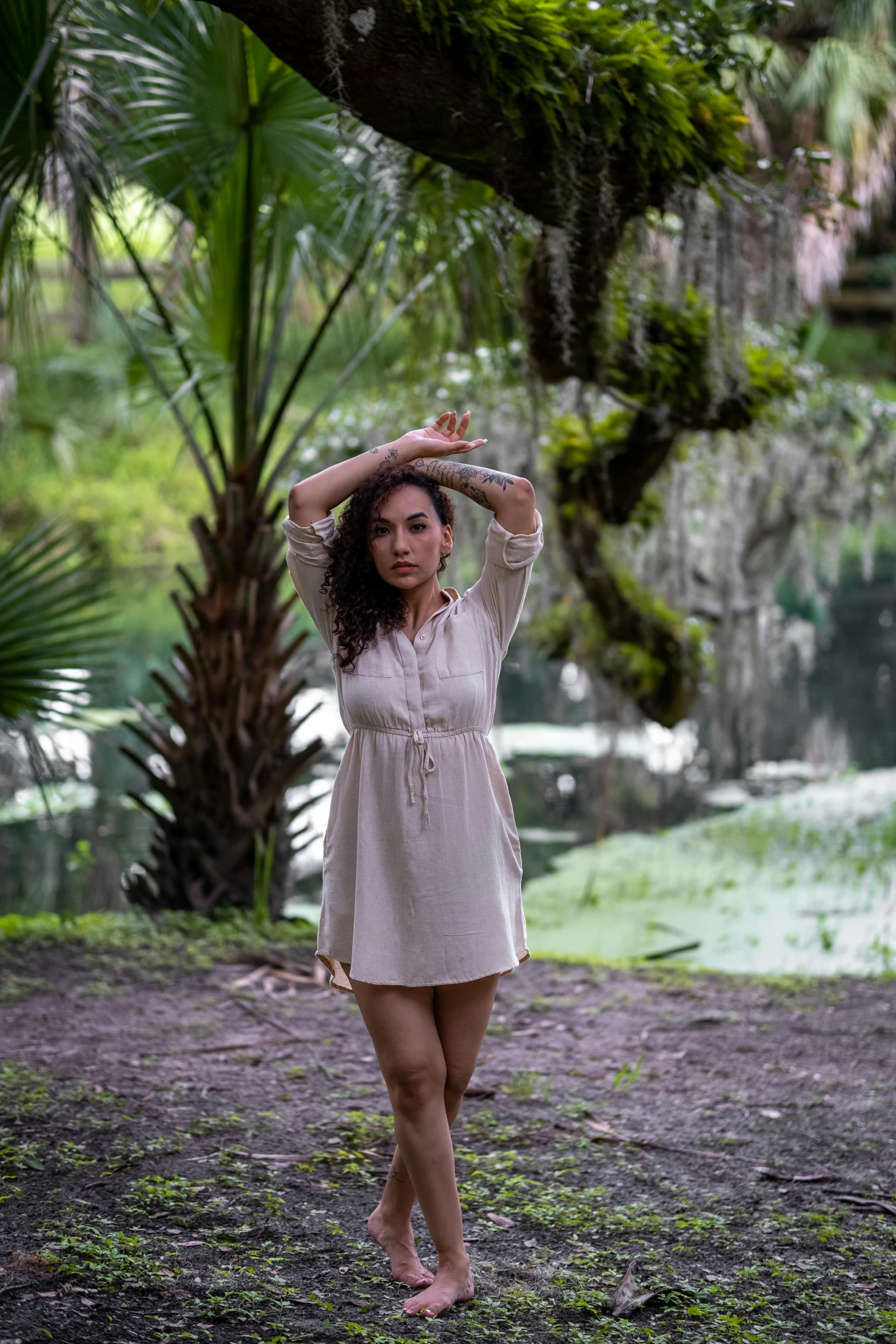 the young woman is standing under the large tree