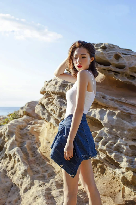 a woman wearing denim shorts standing next to rocky formations