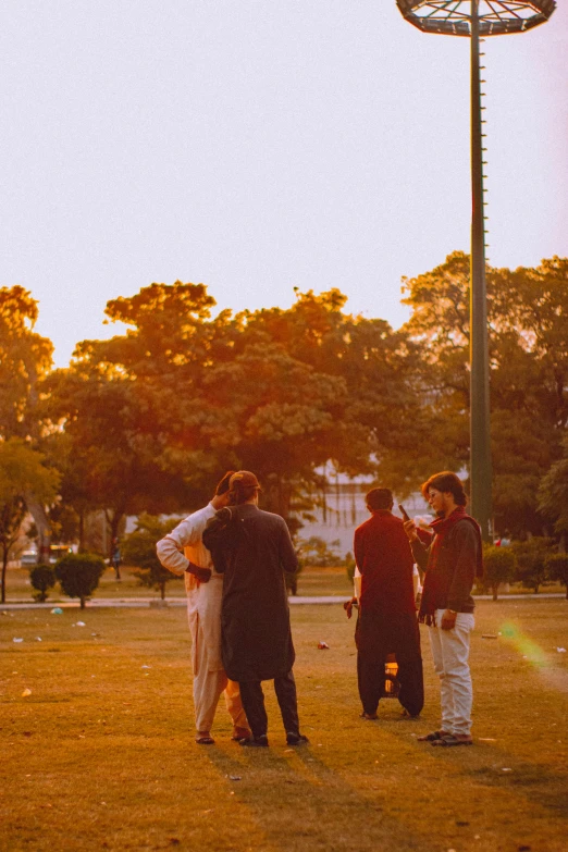 three people standing in a grassy field with trees