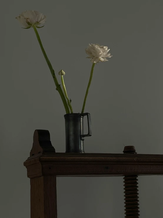 three white flowers sit in a black cup on a ledge