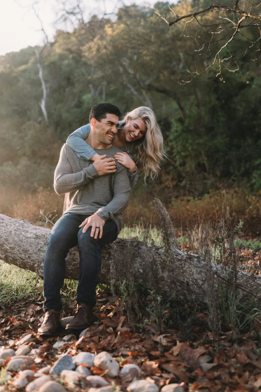 couple sitting on tree log together, in the woods