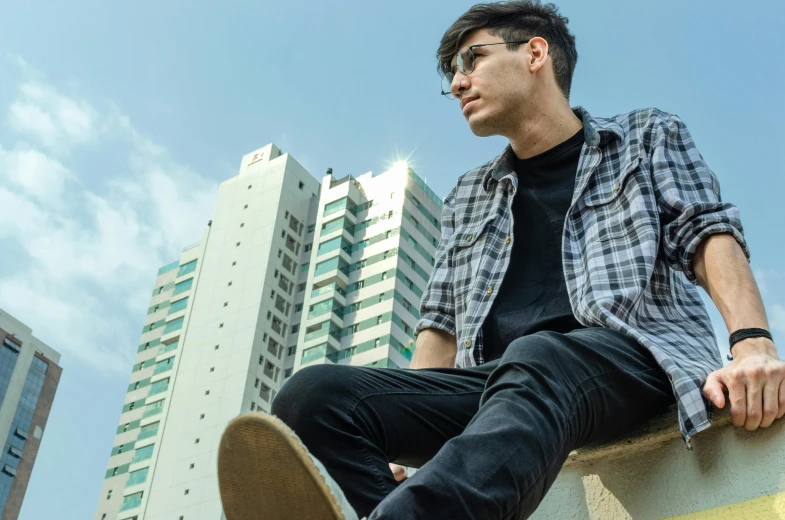 a young man is sitting on a ledge with his skateboard