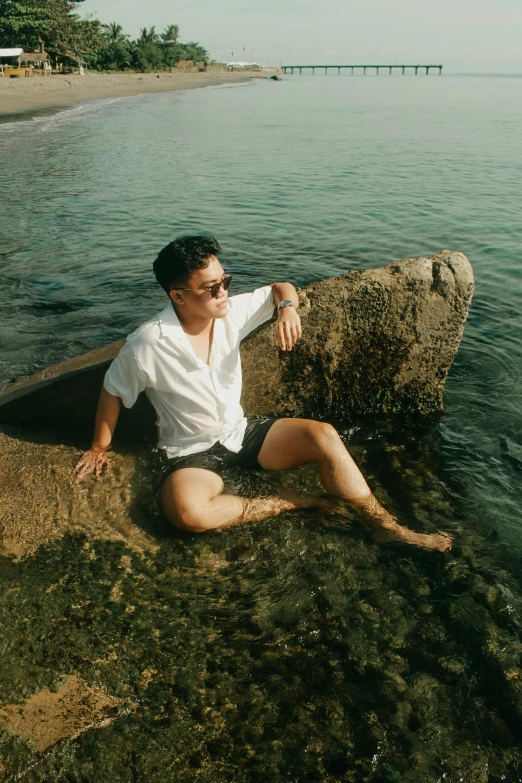 a person sitting on top of a rock near the ocean