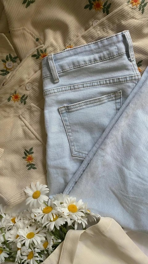 two white daisies in a vase with some fabric