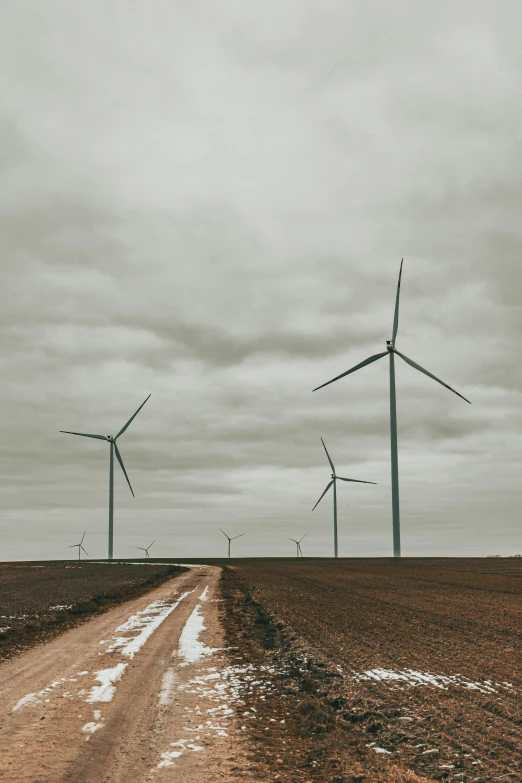 three wind turbines are standing above an empty field