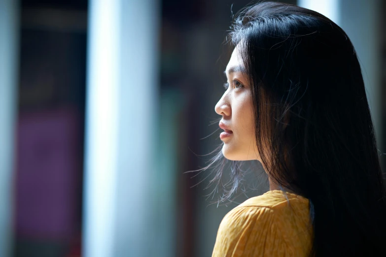 a woman with long black hair is wearing a yellow top