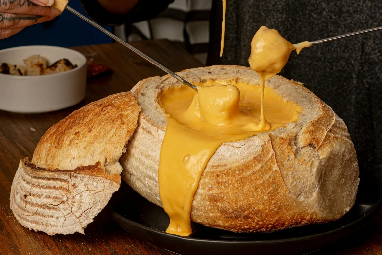 person dipping cheese into bread on the table