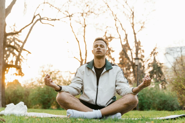 man sitting in yoga pose in the middle of grassy area