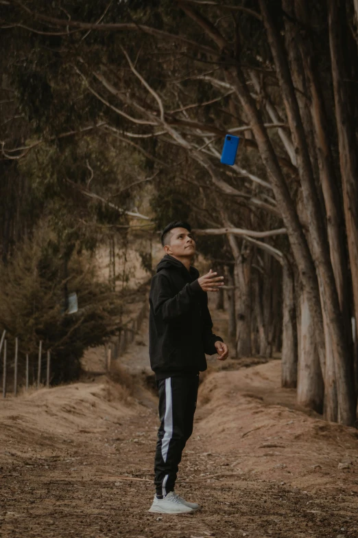 a man standing in front of some trees while looking up