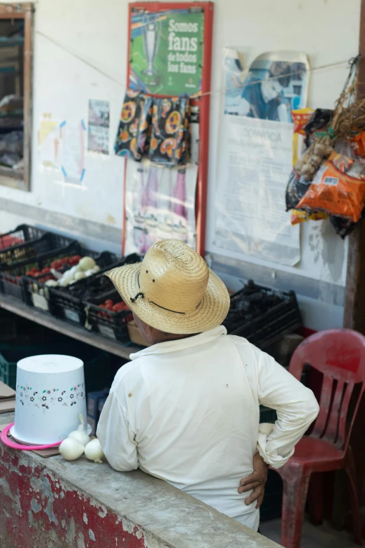 a man sitting down in a tan hat with an ice cream vendor behind him