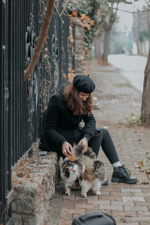 a woman sitting on the side of a road with two dogs