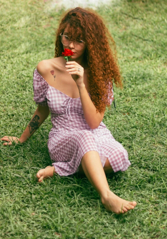 the woman is sitting in the grass with her finger on her lips