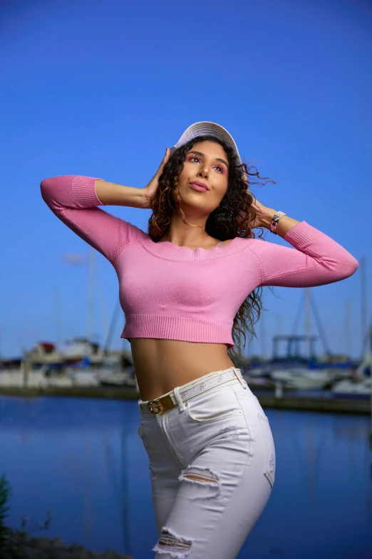 a woman is posed with her hands behind her head