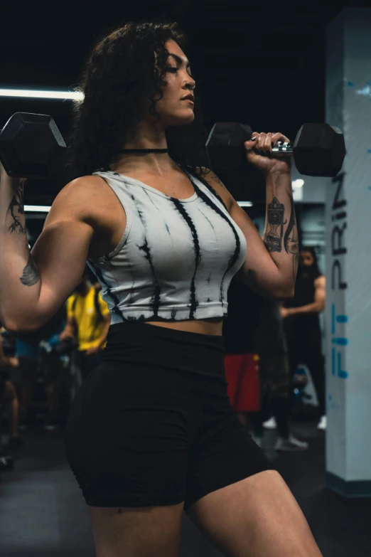 a woman holding dumbs in her hands, while standing inside a gym