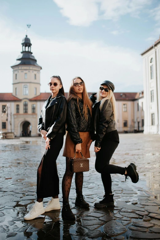 three woman are posing for the camera near a castle