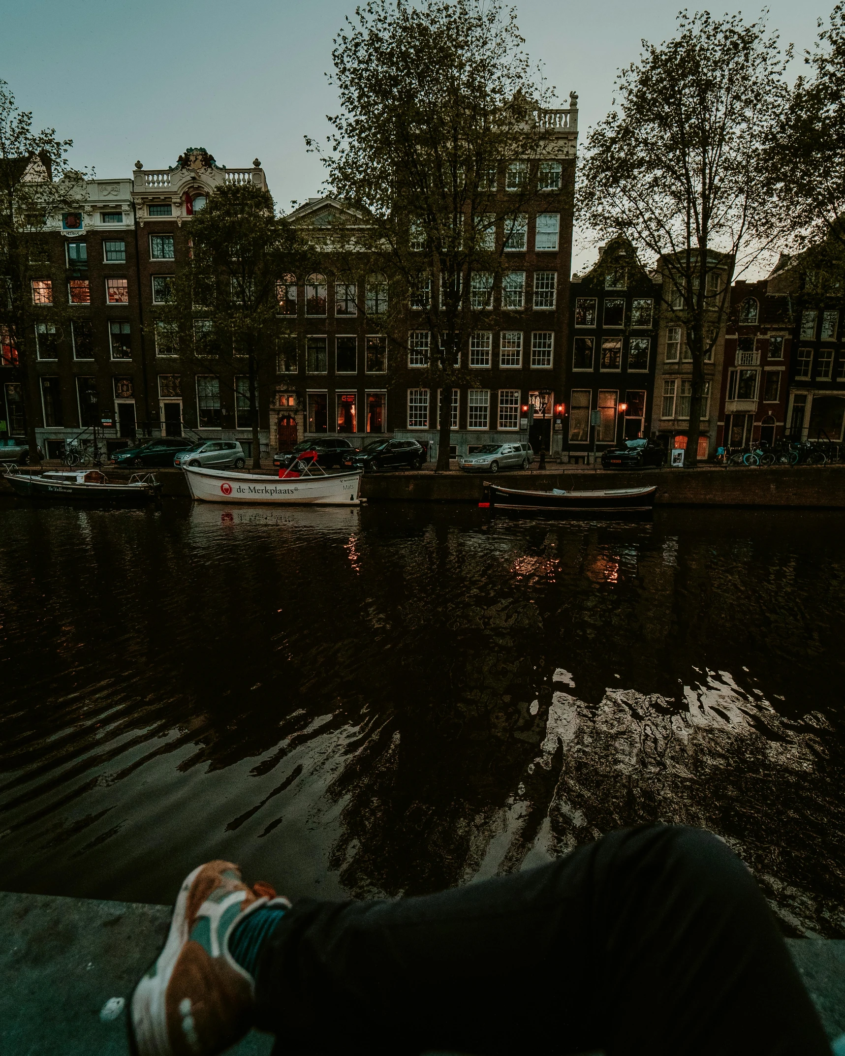 someone lying down on a sidewalk beside the water in a harbor