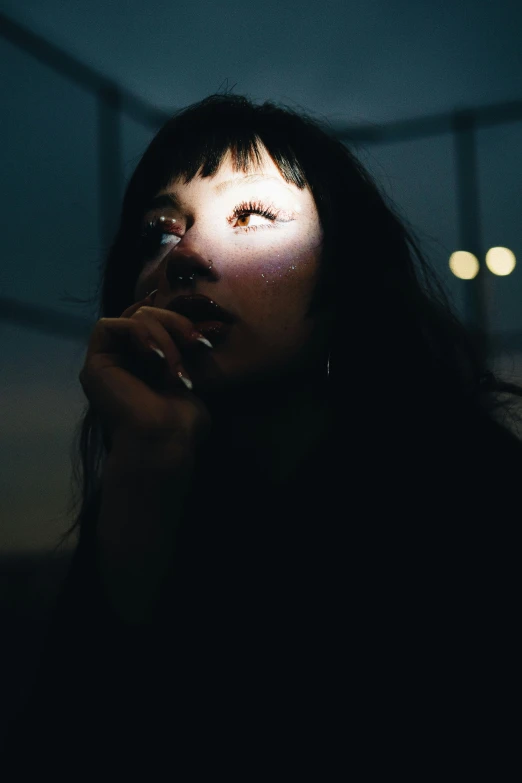 a dark - haired woman smoking in a darkened room