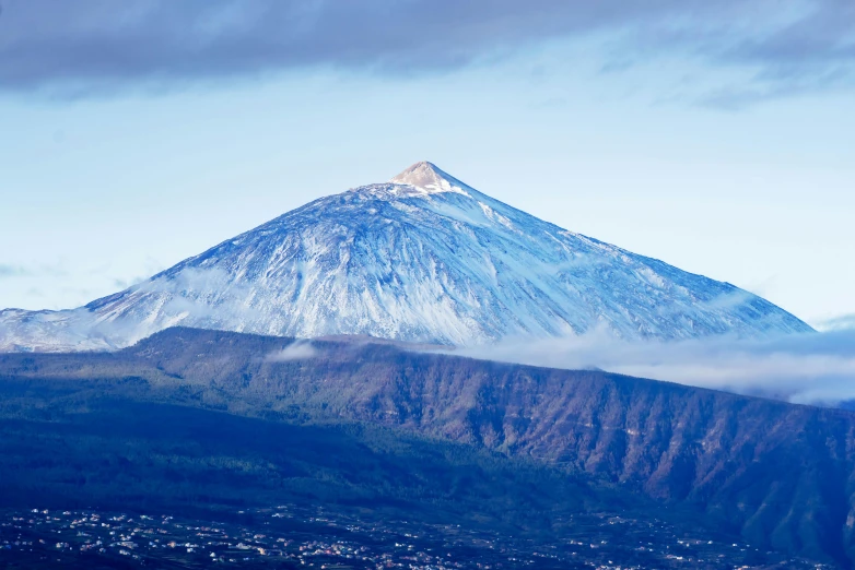 a snow covered mountain in the mountains surrounded by clouds