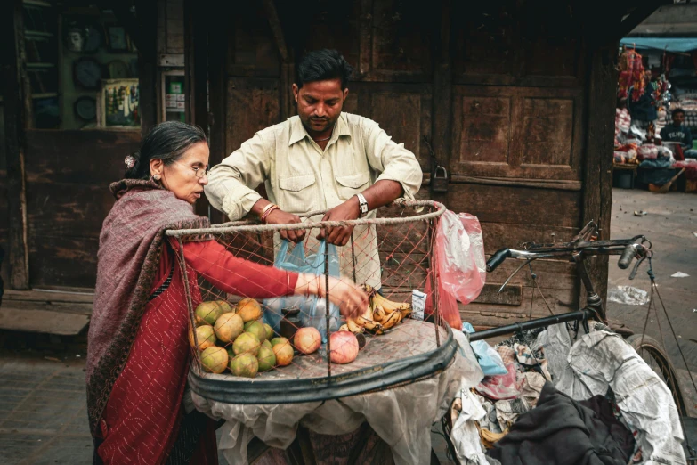 a man and woman are purchasing fruit on the street