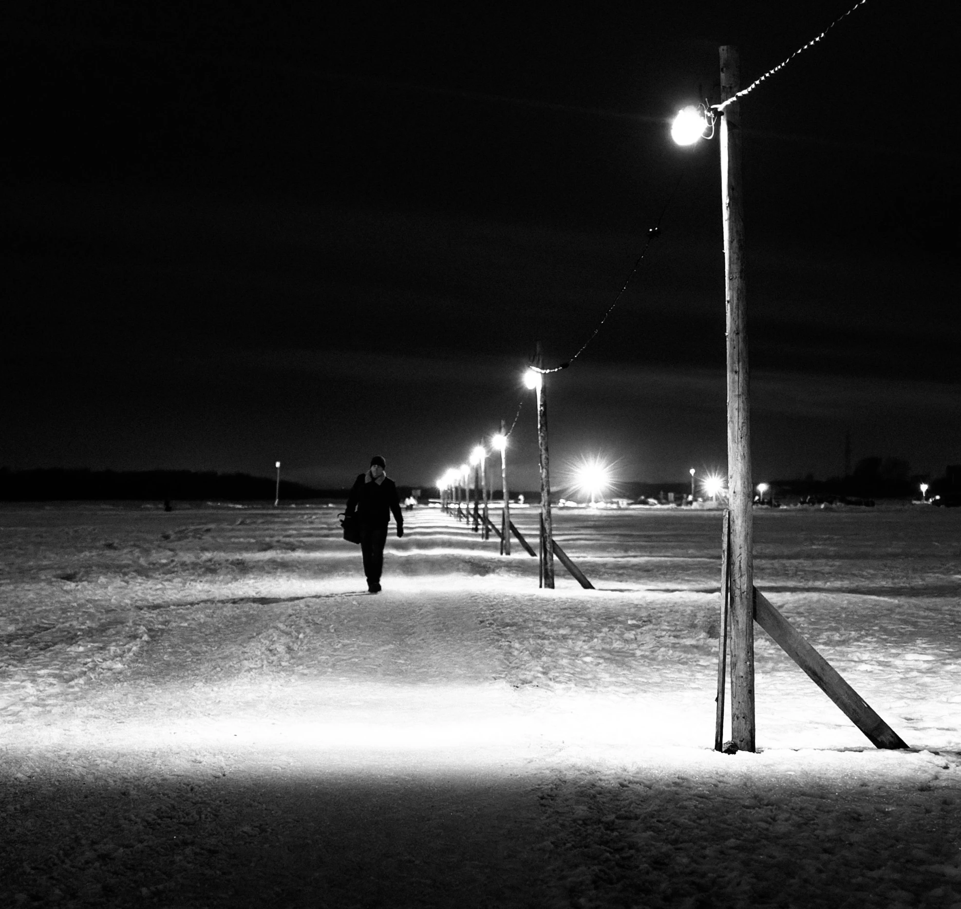 a man walks along a snowy path at night