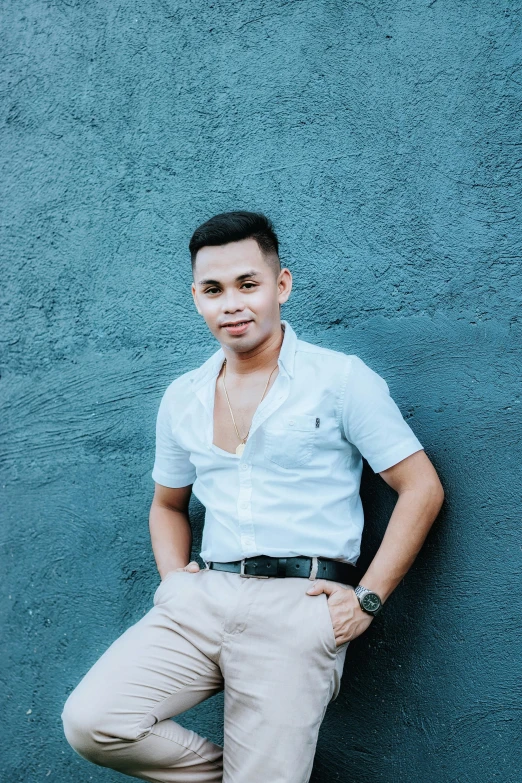 a man with his legs crossed leaning against a wall