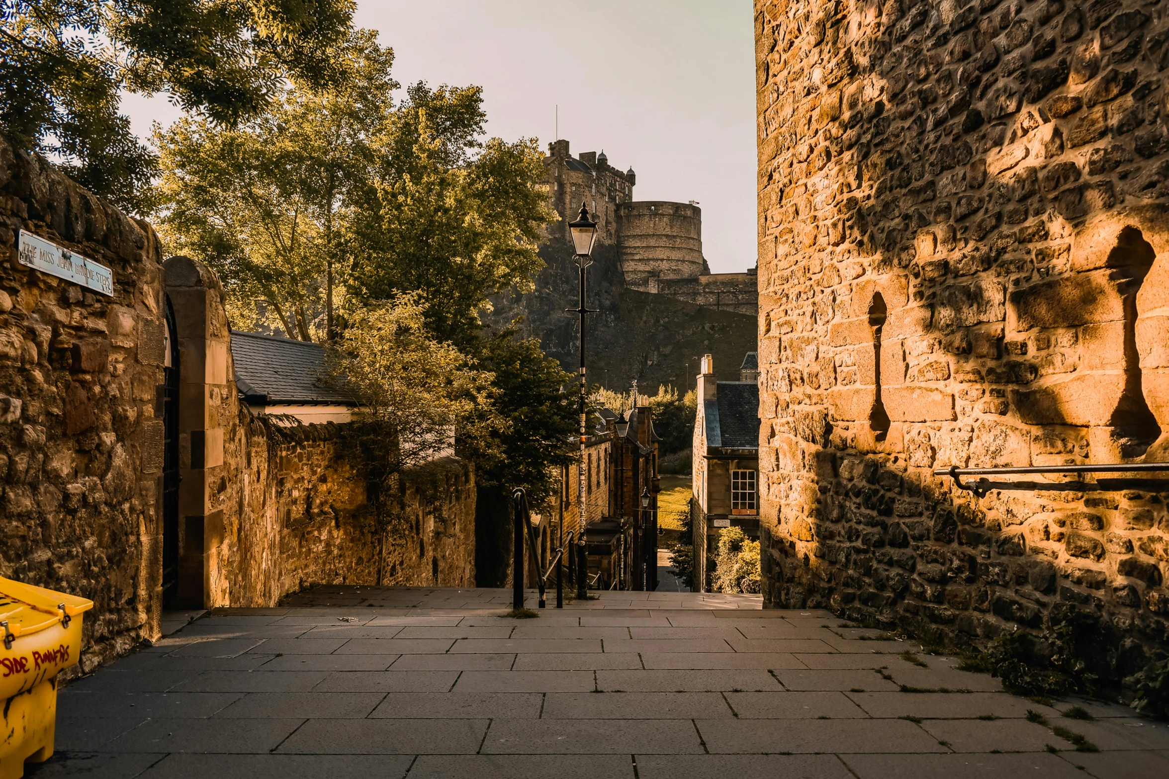 the side walk is shaded with stone buildings