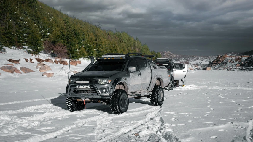 black truck with snow tires parked on snowy road