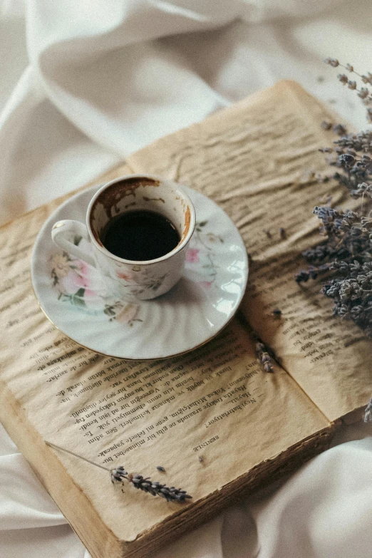 an open book on a bed with a cup of coffee