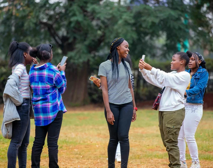 a group of women standing around one another holding onto their cell phones