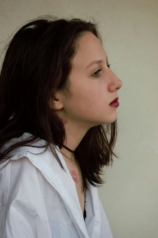 a woman has her nose pressed closed while wearing a white shirt