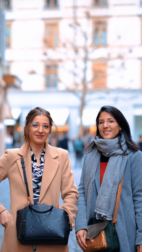 two women holding large black bags standing in an open courtyard