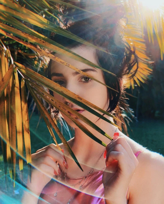 an attractive woman standing under a palm tree