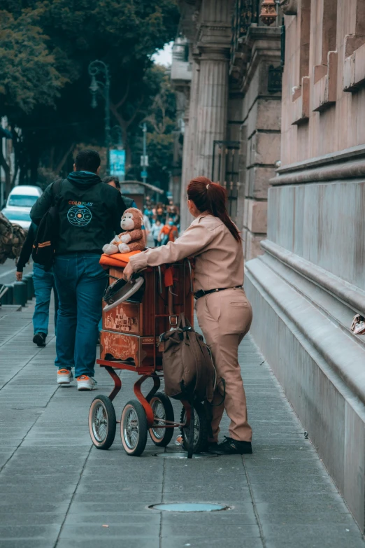 a women hing a baby in an orange cart down a city street