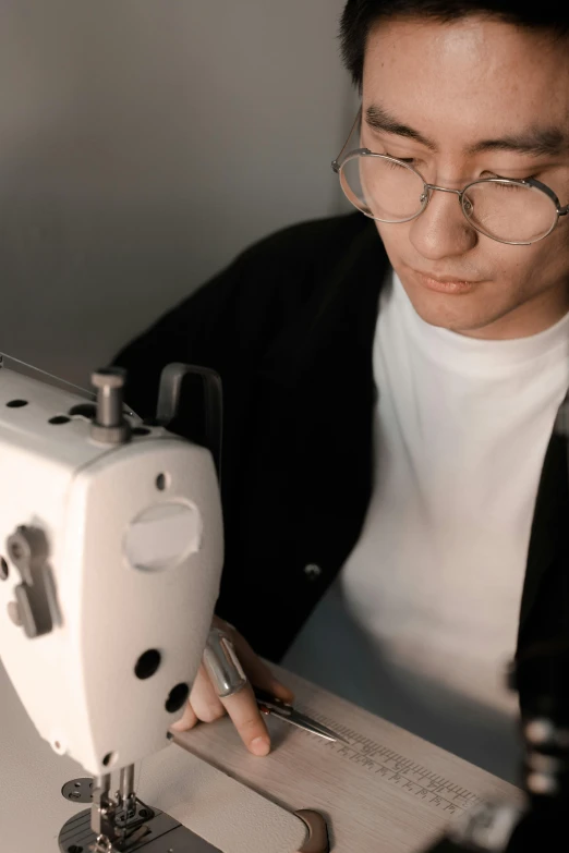 a man who is looking down at a white sewing machine