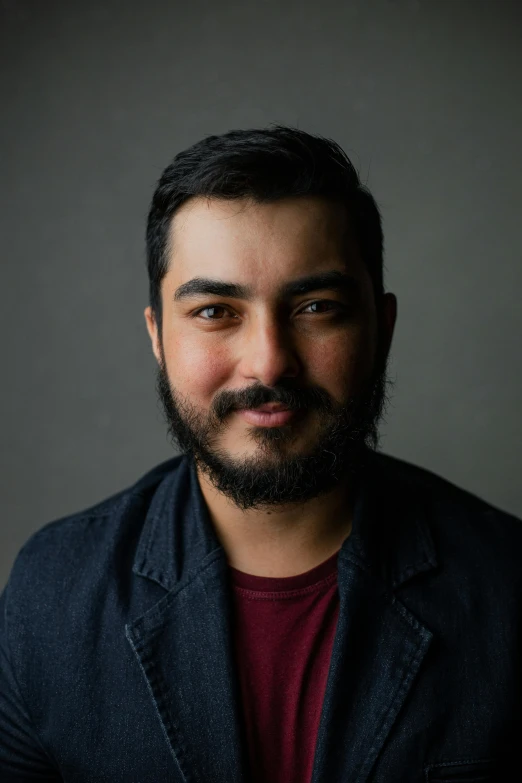 a close up of a person wearing a blazer and a red shirt