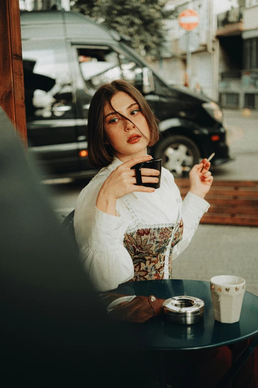 a woman in a dress smokes a cigarette while holding her cell phone