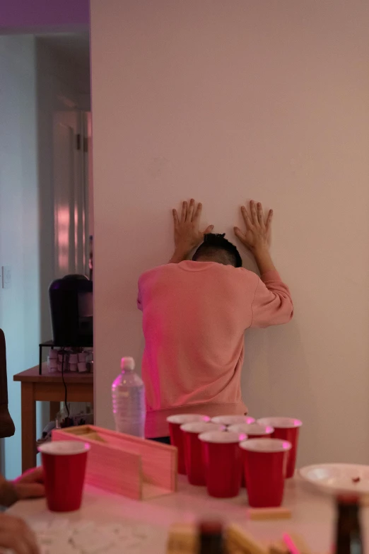 a child hiding behind cups and holding their hands up