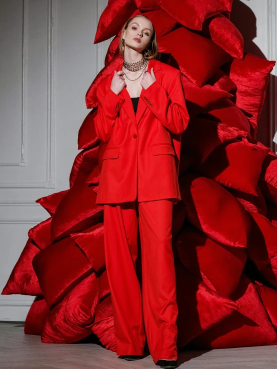a woman in a red suit stands near a stack of red plastic sheets