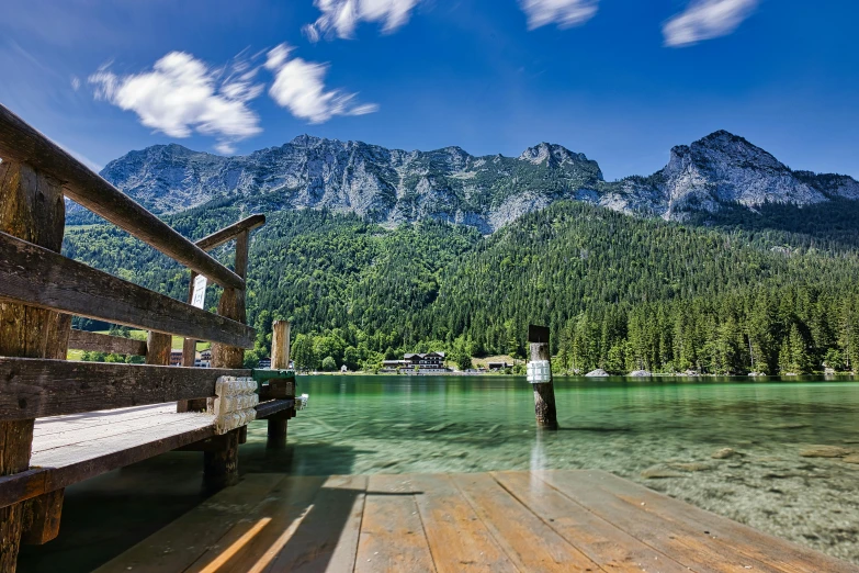 man standing at dock on lake with mountain backdrop