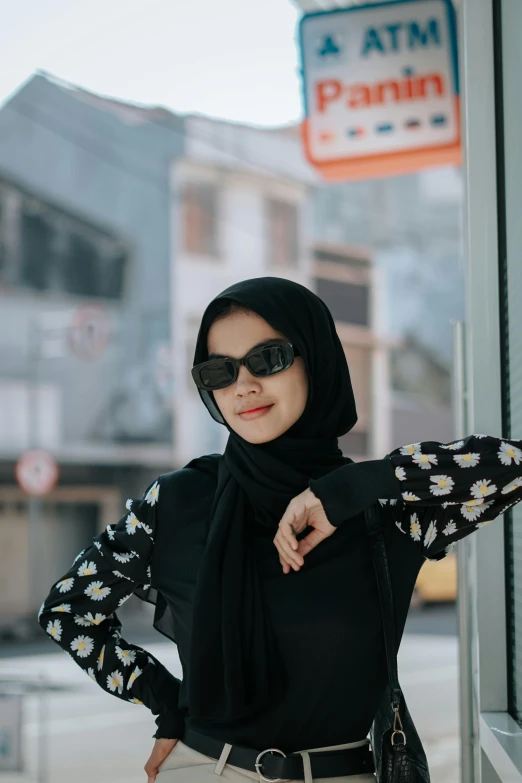 a woman in sunglasses wearing a black top and a floral sweater