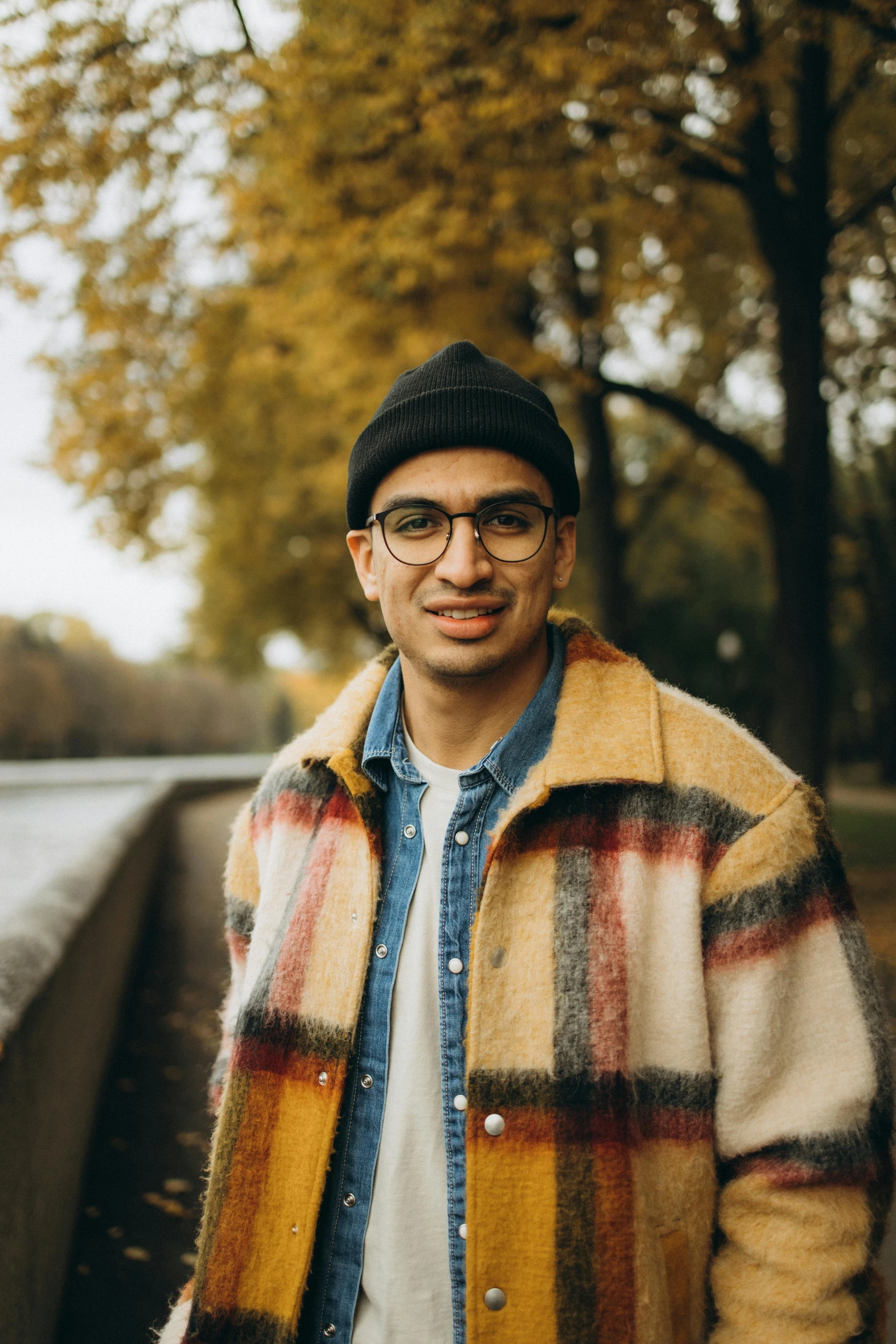 a man standing next to a tree wearing glasses