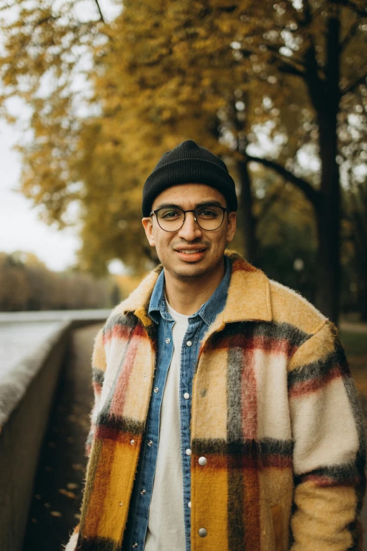 a man standing next to a tree wearing glasses