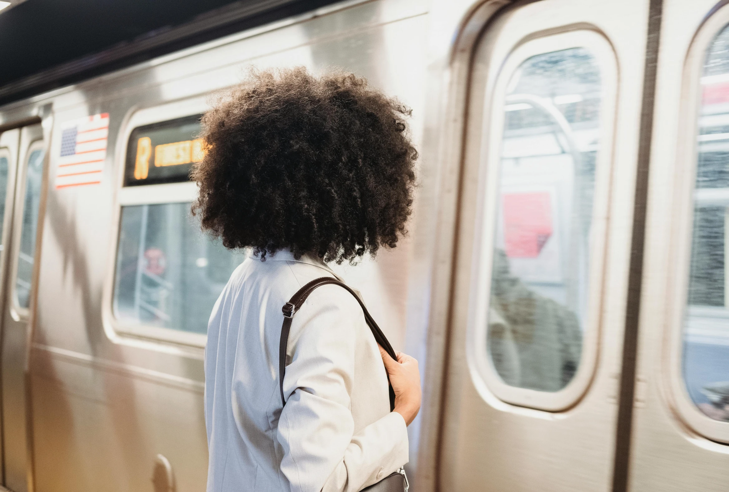 a woman with curly hair looking out the train window