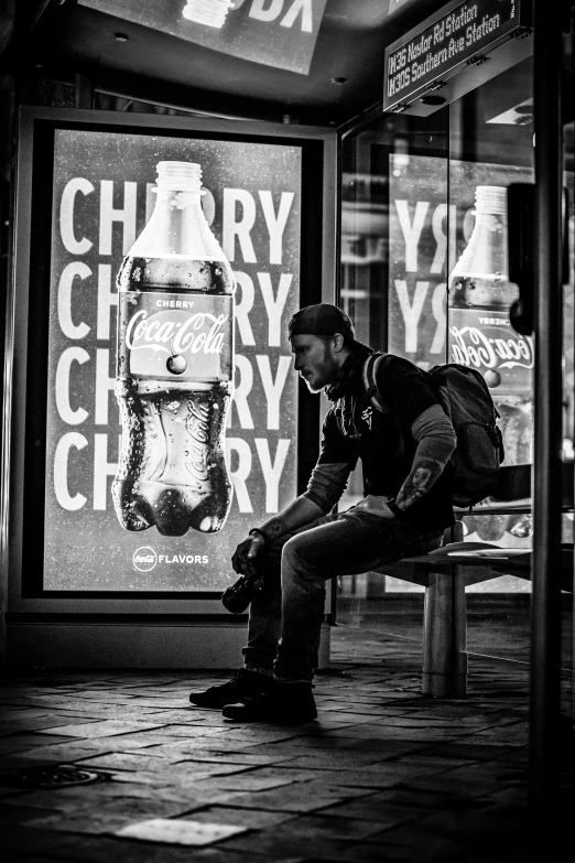 a man sitting on a bench next to a giant bottle