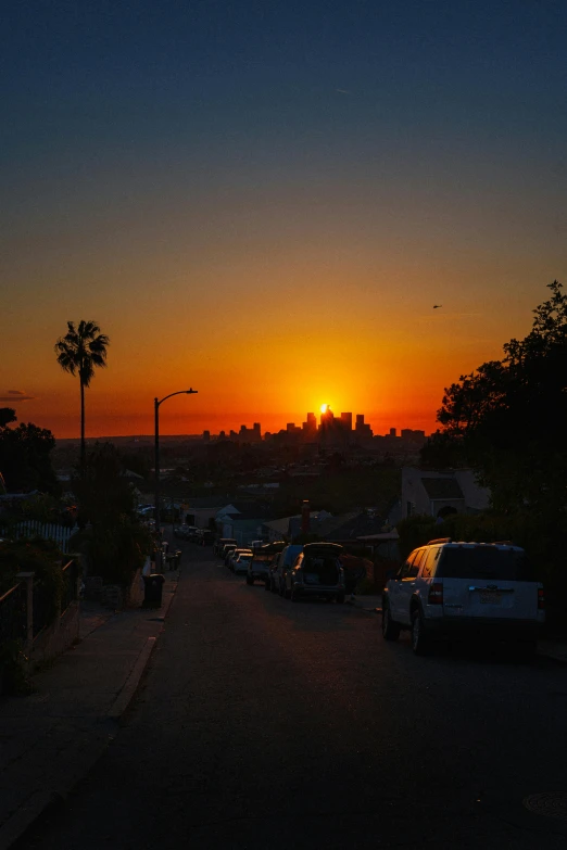 the sun sets in a city, with traffic