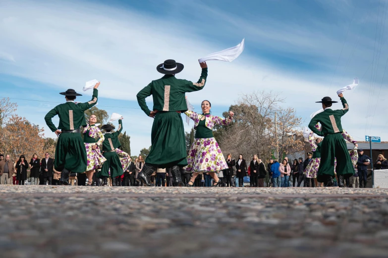 a group of people wearing dresses and hats and holding a white sheet